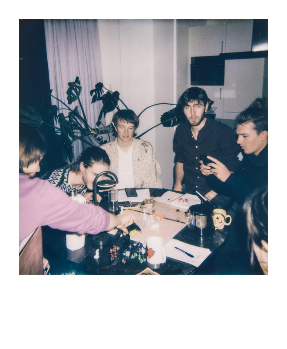 Freundesgruppe spielt Dungeons & Dragons am Tisch mit Würfeln und Charakterbögen