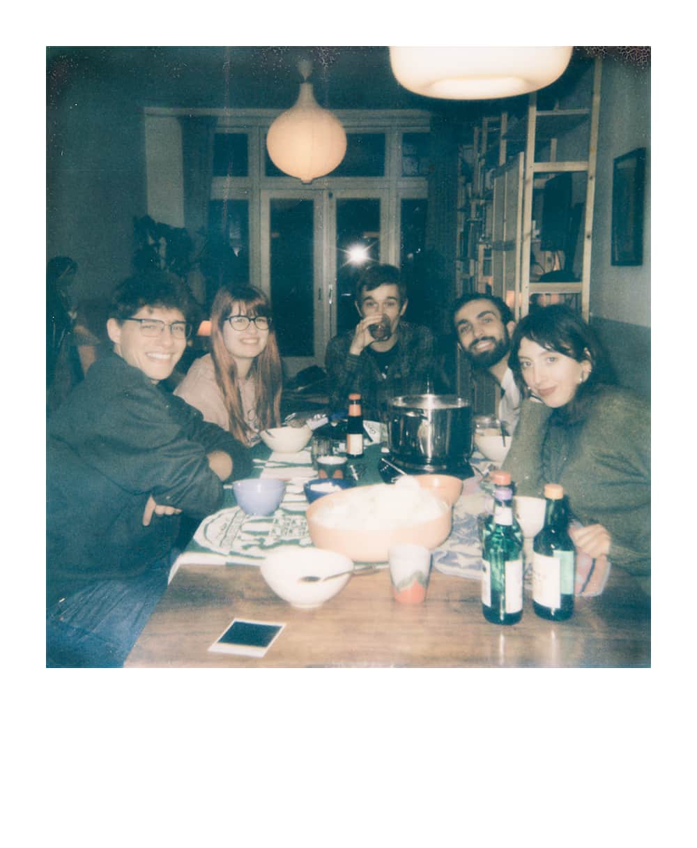 Fünf Freunde versammelt in einem gemütlichen Wohnzimmer um einen Tisch mit Spielkarten und Getränken während einer Tabletop-RPG-Session